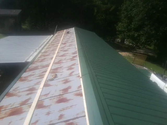 Old rusted panels beside newly installed green metal roofing — Wind Damage Roof Repair by Roofing Brothers in Sterling